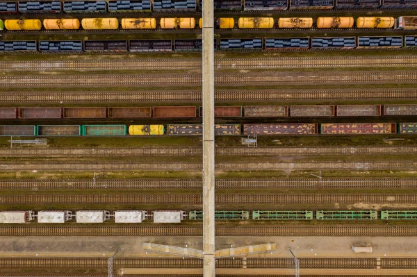 Vista aérea de trenes de carga de colores con mercancías y puente en la estación de tren . — Foto de Stock