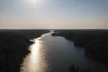 Yaz günü güneş ve ormanın yansımalarıyla büyük nehrin drone görüntüsü.