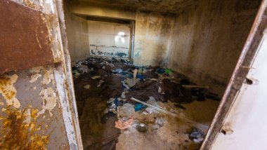 Dağınık enkaz ve duvarların soyulduğu terk edilmiş bir oda. Suriye, Sednaya Cezaevi.