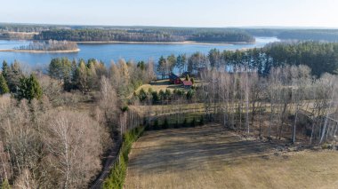 Etrafı ağaçlarla çevrili sakin göl manzaralı bir ev..