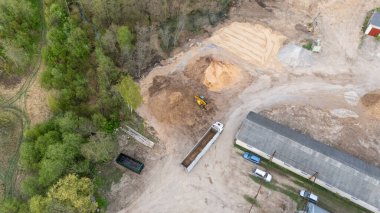 Endüstriyel alanda bir kamyona odun parçaları yükleyen bir yükleyicinin hava görüntüsü