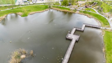 Büyük bir gölet ve ahşap geçitli bir parkın havadan görünüşü.