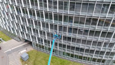 Çalışanlar asansör kullanarak modern cam binaların camlarını temizliyorlar..