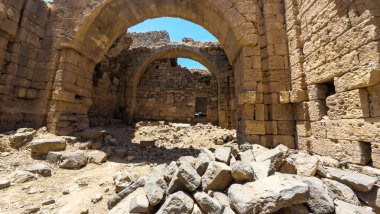 Gökyüzünün altında kadim taş kalıntıları, kemerler ve dağınık kayalar. Antik Dara şehri, Suriye.