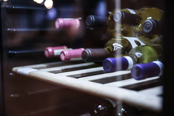 Bottles of wine are in a special refrigerator. different necks of wine bottles. wine fridge with bottles. Wine bottles on the shelf in the restaurant