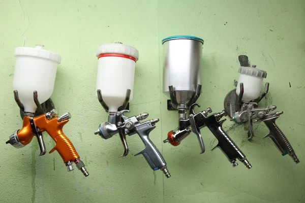 spray guns are hanging on a hooks in the painting chamber. different paint guns hangs in a row on the wall