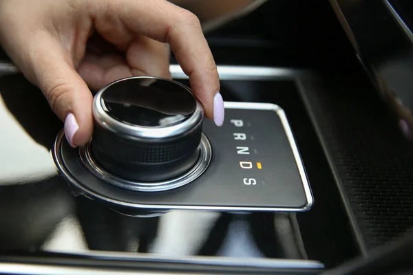 the joystick gear shift of the automatic transmission. women's hand includes a drive mode on the automatic transmission close-up