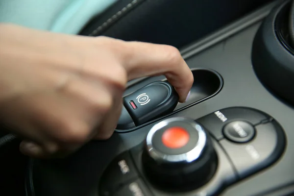 female hand pulls the hand brake button in a modern car. electric hand brake in a car