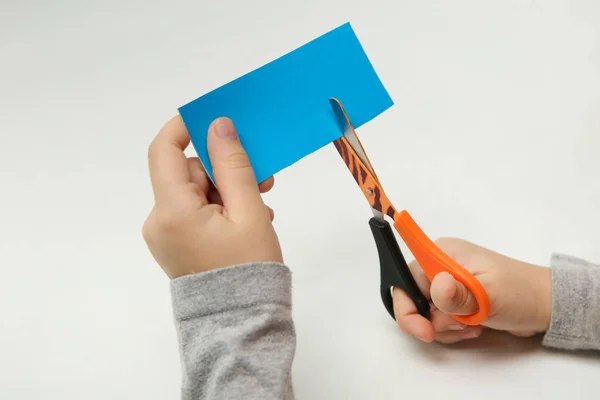 Tesoura Mãos Criança Uma Tira Papel Azul Fundo Branco Papel — Fotografia de Stock