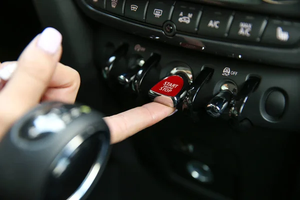 female\'s finger presses the toggle switch to start the car engine. red toggle switch engine start close-up. start engine button