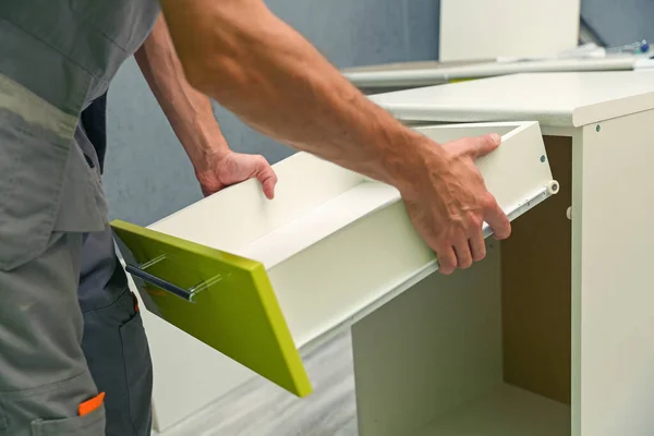 worker assembles furniture in the kitchen. furniture assembly service