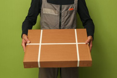 Karton kutu tutan bir yükleyici. Teslimat servisi çalışanı bir kutu tutar.