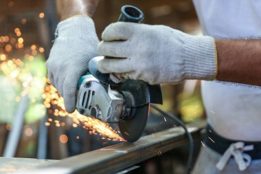 Ustanın elleri, metali öğütücüyle gördü. Metal atölyede çalışıyor. Kapatın..