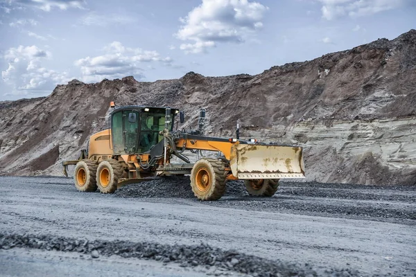 Yol inşaatındaki kumlu yamacın arka planındaki motor gradyatör zemini düzleştirir