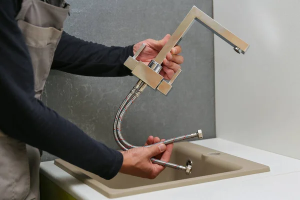 Tesisatçı mutfak musluğu kuruyor. Apartman yenileniyor.