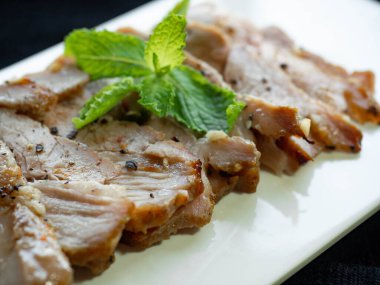 Izgara domuz eti, sarımsak, biber, beyaz bir tabağa koy, biber serp, yüzüne nane yaprağı sür, Tayland yemeği koy.