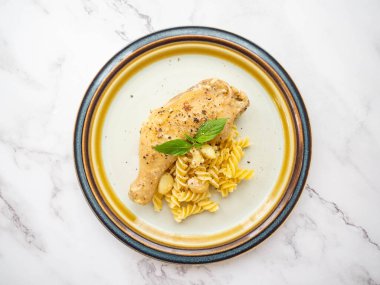 Ana sarımsaklı sarımsaklı sarımsaklı tavuk, tereyağı, tavuk, makarna beyaz bir tabağa yerleştiriliyor, yüzü fesleğenle kaplı, beyaz arka plan