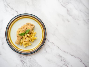 Ana sarımsaklı sarımsaklı sarımsaklı tavuk, tereyağı, tavuk, makarna beyaz bir tabağa yerleştiriliyor, yüzü fesleğenle kaplı, beyaz arka plan