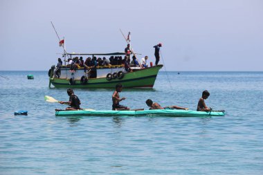 Küçük çocuklar kano gibi kayık oynuyorlar.