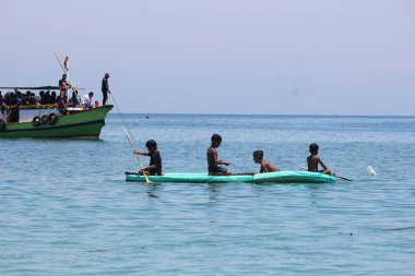 Küçük çocuklar kano gibi kayık oynuyorlar.