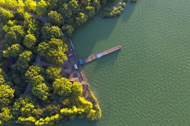 Ağaçlar ve gölün yanındaki ahşap köprü. Fotoğraf: Suzhou, Çin.