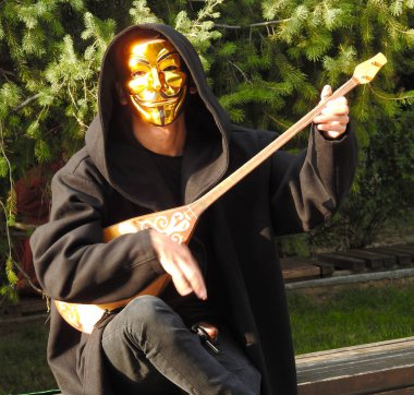 Bir Altın maske Guy Fawkes, aynı zamanda Anonymus maskesi olarak bilinen bir sokak müzisyeni ulusal Kazak enstrüman çalış - Dombra.