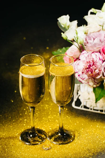在黑色背景上与黄金的美丽玫瑰和香槟杯的花束 — 图库照片