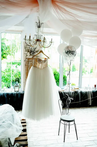 Odadaki askıda asılı güzel bir gelinlik. Düğün hazırlığı..