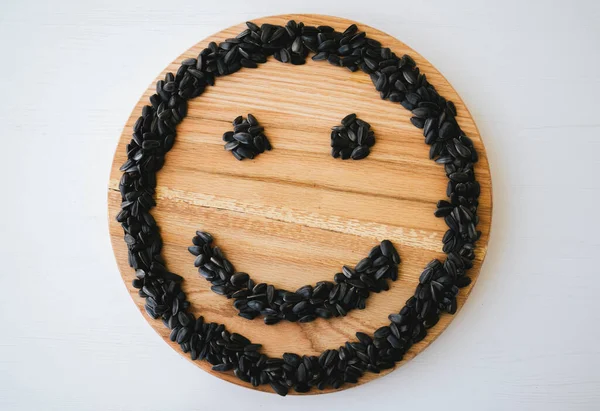 Tahta arka planda ayçekirdeğinden yapılmış gülücük şekli