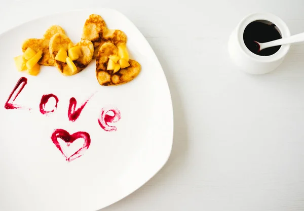 Beyaz arka planda şeftali parçaları olan Amerikan kalp şeklinde krepler..