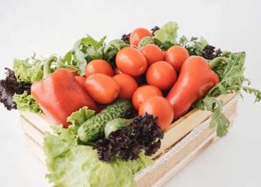 Beyaz arka plandaki ahşap kutunun içindeki taze sebzelerin yakın plan fotoğrafı..