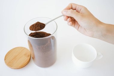 Kaşık ve kahve tutan bir insan eli. Kahve hazırlığı..