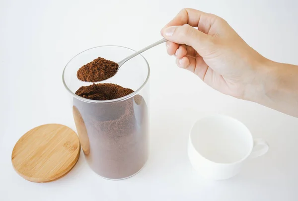 Kaşık ve kahve tutan bir insan eli. Kahve hazırlığı..