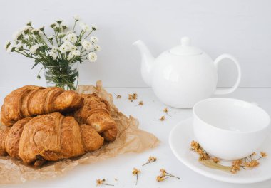 Lezzetli kruvasan karışımı beyaz çaydanlık ve fincanla yakın plan..