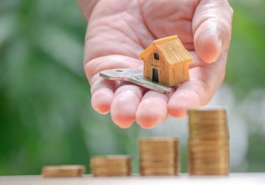 Ev veya ev modeli ve sikkeler üzerinde el ile ev anahtarı. Kavramı kredi için mülkiyet merdiven, finans, mortgage, gayrimenkul yatırım, vergiler ve bonus.