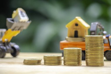 Ev veya ev modeli sikke yığını üstünde. Kavramı kredi için mülkiyet merdiven, finans, mortgage, gayrimenkul yatırım, vergiler ve bonus.