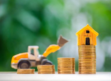 Ev veya ev modeli sikke yığını üstünde. Kavramı kredi için mülkiyet merdiven, finans, mortgage, gayrimenkul yatırım, vergiler ve bonus.