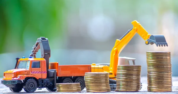 The yellow truck toy behind coins stack save the money invest for the future concept business, financial, tax and bonus. Logistics and transportation concept.