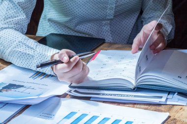 Kadın iş yazma ve şirket masasında bazı kağıtları okuyor. 