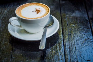 Yaprakları ile Kahve fincanı yenileme ile çalışmaya başlamadan önce sabah siyah ahşap masada latte sanat köpük şekli latte sanat köpük. 