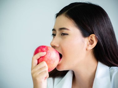 Beyaz arka planda izole ofis mutlu ile diyet için bir elma ısırmak güzel kadın yakın. Yeme ve sağlık konsepti.