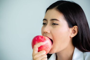 Beyaz arka planda izole ofis mutlu ile diyet için bir elma ısırmak güzel kadın yakın. Yeme ve sağlık konsepti.