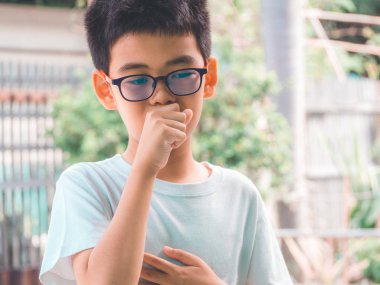 Asyalı çocuk öksürük ve iyi hissetmiyor. Soğuk algınlığı ya da bronşit belirtileri gibi. Sağlık hizmetleri kavramı.