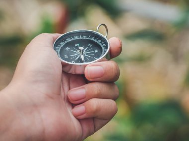 Ormanda ya da ormanda seyahat ederken ve dağa ya da tepeye giden bir macera rotası ararken manyetik altın pusula kullanan bir çocuk eli. Destansı manzara konsepti.