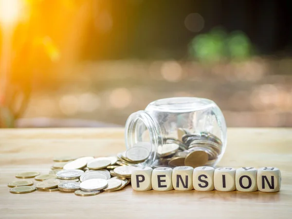 Coins in jar with wooden block written PENSION  text on wood table to saving money for retirement financial and pension annuity insurance. Concept for loan,property,financial.