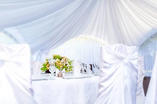 Wedding simple outdoor table setting in a white outdoor tent.