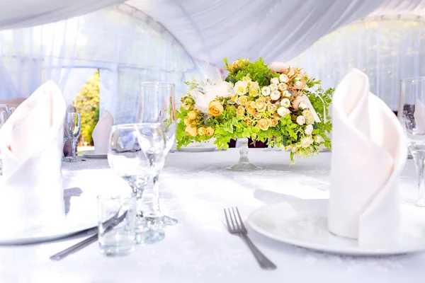 Mesa de boda con un mantel blanco en una carpa blanca al aire libre — Foto de Stock