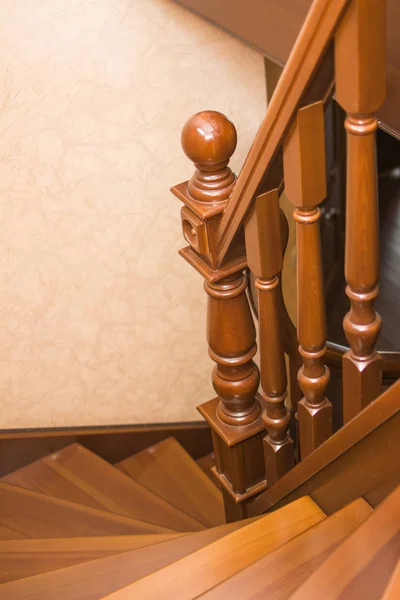 Brown spiral wooden staircase with wooden railing and steps