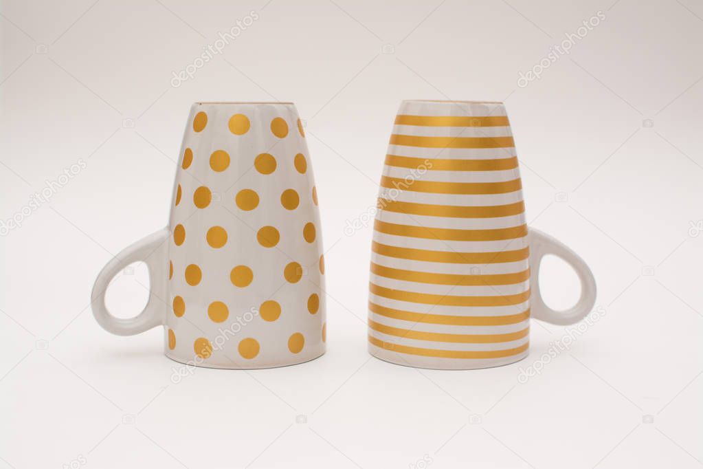 Two upturned cups of coffee. Cups for coffee with a pattern in the form of circles and stripes upside down on a white background.