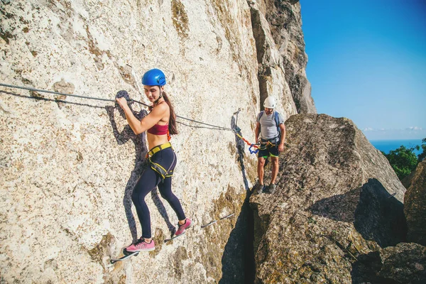 Woman and man climbing mountain.